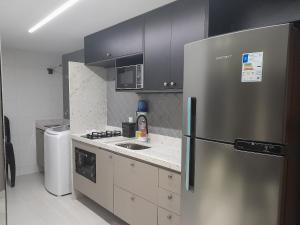 a kitchen with a stainless steel refrigerator and a sink at Amaranth Beach Class - Miramar Hospedagens in Ilha da Restinga