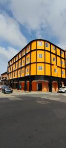 un grande edificio giallo con auto parcheggiate in un parcheggio di La Cubana Hotel & Suites a Colón