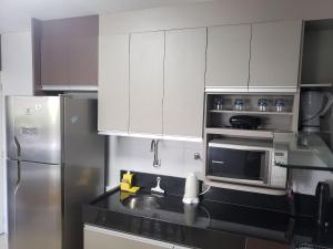 a kitchen with white cabinets and a stainless steel refrigerator at Acrópole - Tambaú in Tambaú