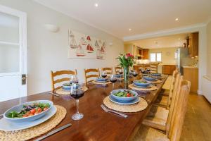 a dining room with a long wooden table with plates of food at Turret House, Thorpeness - Close to the beach, Thorpeness Lake , Thorpeness Hotel, Golf and Country Club - Aldeburgh Coastal Cottages in Thorpeness