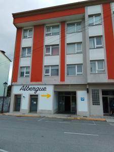 un immeuble d'appartements avec un panneau albuquerque sur son côté dans l'établissement Hostel & Rooms O Albergue da Meiga, à Padrón