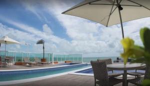 - une piscine avec une table, des chaises et un parasol dans l'établissement Atlântico Norte, à João Pessoa