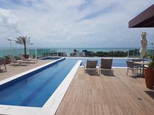 una piscina con sillas y vistas al océano en Atlântico Norte, en Tambaú