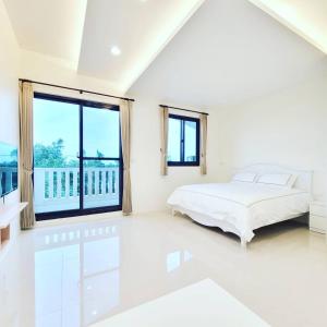 a white bedroom with a bed and a large window at Fay Homestay in Yilan City
