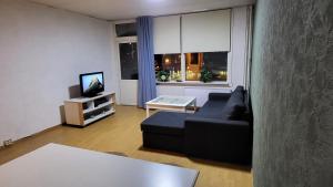 a living room with a black couch and a tv at Laksevåg Apartment in Bergen