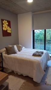 a bedroom with a large white bed with a window at Usina AS Salta in Salta