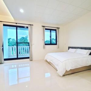 a white bedroom with a bed and large windows at Fay Homestay in Yilan City