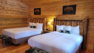 two beds in a room with wooden walls at Riverfront Motel & Cabins in Thompson Falls