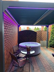 un patio con una mesa y sillas bajo una iluminación púrpura en Apartament "Love Island" z Jacuzzi SPA dla Dwojga en Gniezno