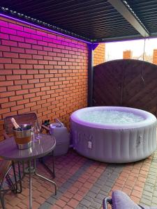 Un grand bain à remous est installé sur une terrasse avec une table. dans l'établissement Apartament "Love Island" z Jacuzzi SPA dla Dwojga, à Gniezno
