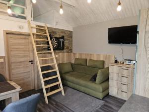 ein Wohnzimmer mit einer grünen Couch und einer Leiter in der Unterkunft chatka Tatralandia 433 Sofinka in Liptovský Mikuláš