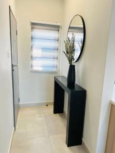 a black table with a mirror and a vase with flowers at E105 Sarona City Flat E105 in Gaborone