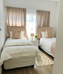 a bedroom with two beds and a window at E105 Sarona City Flat E105 in Gaborone