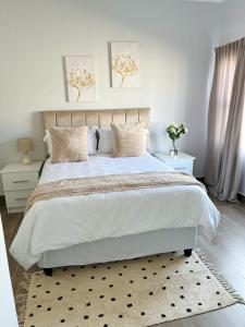 a bedroom with a large white bed with a rug at E105 Sarona City Flat E105 in Gaborone