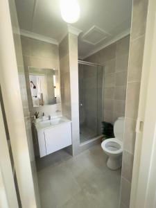 a bathroom with a toilet and a shower and a sink at E105 Sarona City Flat E105 in Gaborone