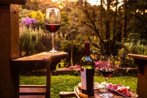 Una botella de vino y dos copas en una mesa. en Pousada Vila Suiça - Monte Verde en Monte Verde
