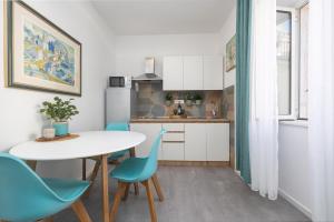 Harmony Apartments في سبليت: مطبخ بطاولة بيضاء وكراسي زرقاء
