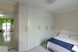 Un dormitorio blanco con una cama y armarios blancos. en Frederico, en Meia Praia