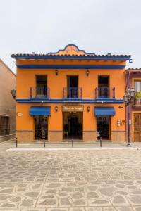 ein orangefarbenes Gebäude mit blauen Balkonen auf einer Straße in der Unterkunft Hotel del Parque Naolinco in Naolinco