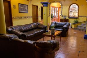 ein Wohnzimmer mit Ledersofas und einem Couchtisch in der Unterkunft Hotel del Parque Naolinco in Naolinco