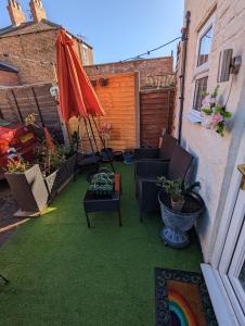 eine Terrasse mit Stühlen, einem Sonnenschirm und Rasen in der Unterkunft Flemingate Cottage, Beverley in Beverley