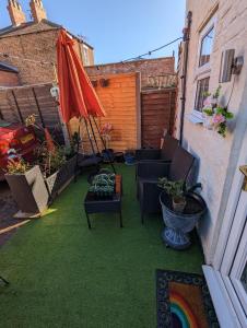 a patio with chairs and an umbrella and grass at Flemingate Cottage, Beverley in Beverley