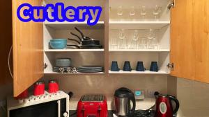 a kitchen with a cupboard filled with dishes and glasses at Two Bedroom Entire Flat, Luxury but Affordable Next to M90 in Fife