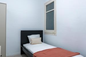 ein kleines Bett in einem Zimmer mit Fenster in der Unterkunft Orange crush Barcelona in Barcelona