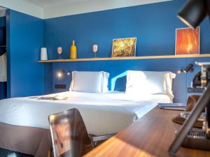a bedroom with a large white bed with blue walls at Mercure Chantilly Resort & Conventions in Chantilly