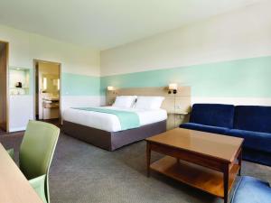 une chambre d'hôtel avec un lit et un canapé dans l'établissement Mercure Chantilly Resort & Conventions, à Chantilly
