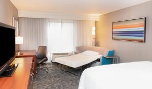 een hotelkamer met een bed, een bureau en een televisie bij Courtyard by Marriott Bloomington in Bloomington