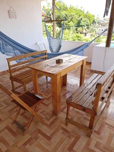 d'une table en bois, de deux chaises et d'un hamac. dans l'établissement Aluguel de suites e Apartamento, à Itacaré