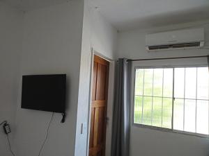 Cette chambre dispose d'une fenêtre, d'une télévision et d'une porte. dans l'établissement Aluguel de suites e Apartamento, à Itacaré