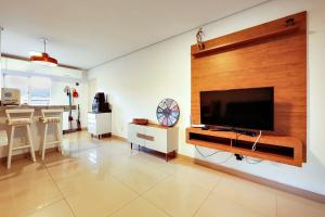 a living room with a large flat screen tv on a wall at Tropical Itapema in Itapema