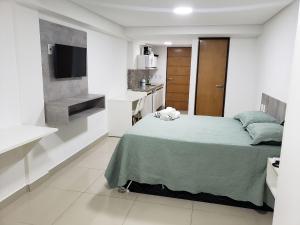 Habitación blanca pequeña con cama y TV en Gold Flat - Miramar Hospedagens, en João Pessoa
