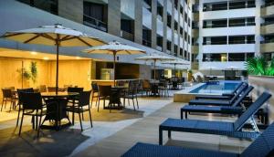 un patio del hotel con mesas y sillas y una piscina en Gold Flat - Miramar Hospedagens, en João Pessoa