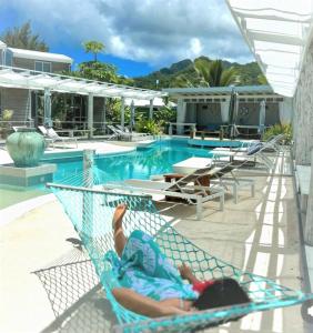 a person laying in a hammock next to a pool at Ocean Escape Resort & Spa in Rarotonga