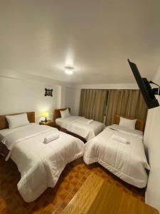 a hotel room with two beds with white sheets at Inka House Hotel in Machu Picchu