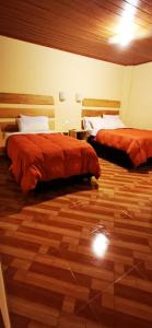 two beds in a room with a wooden floor at Centro Espiritual Hostal Inti Wasi in Machu Picchu