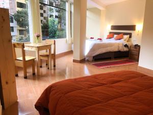 a bedroom with a bed and a table and a desk at Centro Espiritual Hostal Inti Wasi in Machu Picchu