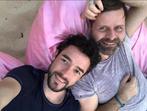Due uomini sono stesi su un letto rosa di 1 Chambre, 1 P'tit dèj', 1 Sourire a Montpellier