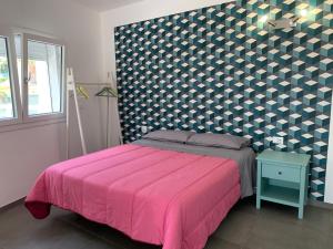 Schlafzimmer mit einem Bett mit rosa Tagesdecke in der Unterkunft White House monolocale in Avola