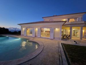 una casa grande con piscina frente a ella en Praia Grande Guest House en Colares