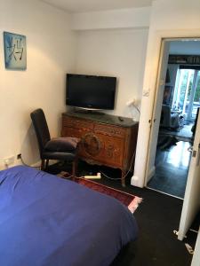 1 dormitorio con TV y escritorio con silla en The Whitehouse, en Londres