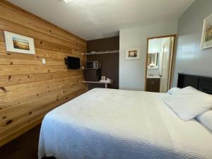 1 dormitorio con cama blanca y pared de madera en Walla Walla Garden Motel, en Walla Walla