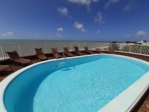 a large swimming pool on a balcony with chairs at Pacific Flat da Miramar in Tambaú