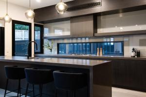 a kitchen with a large island with bar stools at Mysa Daylesford- stylish design with pool in Daylesford