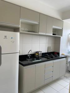uma cozinha com armários brancos e um frigorífico branco em APARTAMENTO ACONCHEGANTE PROXIMO A PRAIA DO ARACAGY em São Luís
