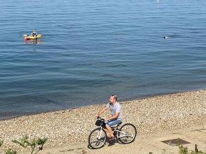 KentにあるBRiSYL BEACH HOUSE, with amazing changing views!の水辺の海岸で自転車に乗る男