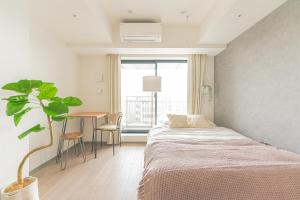 a bedroom with a bed and a table and a plant at i-rent京急蒲田 in Tokyo